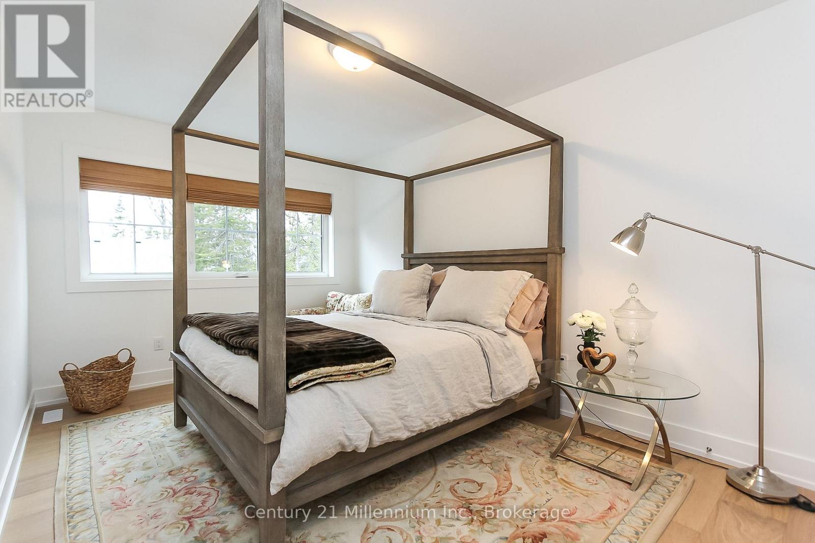 A bedroom with a four poster bed and a glass table with a flower vase on it.