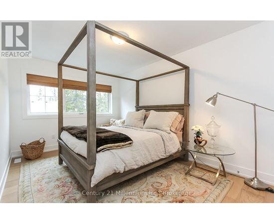 A bedroom with a four poster bed and a glass table with a flower vase on it.