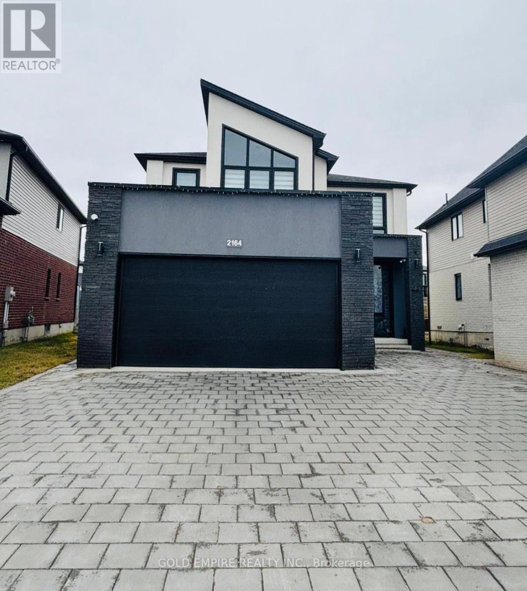 A modern house with a black garage door is for sale.