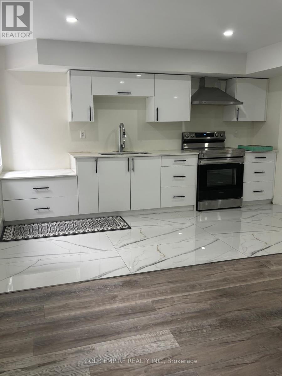 A modern kitchen with white cabinets and a wooden floor.