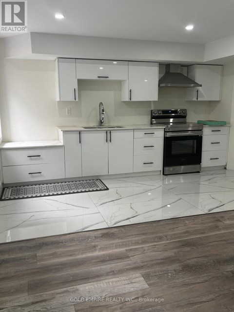 A modern kitchen with white cabinets and a wooden floor.