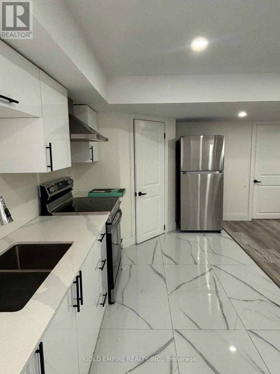 A kitchen with white cabinets and a marble floor.