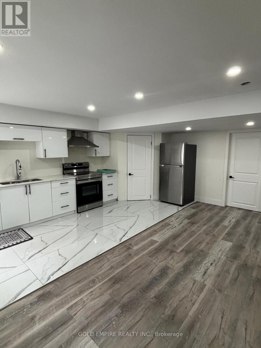 A modern kitchen with white cabinets and a wooden floor.