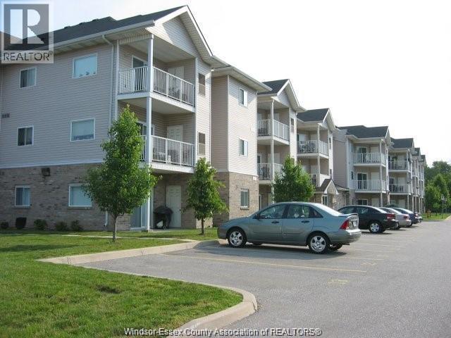 A car is parked in a parking lot in front of apartment buildings.