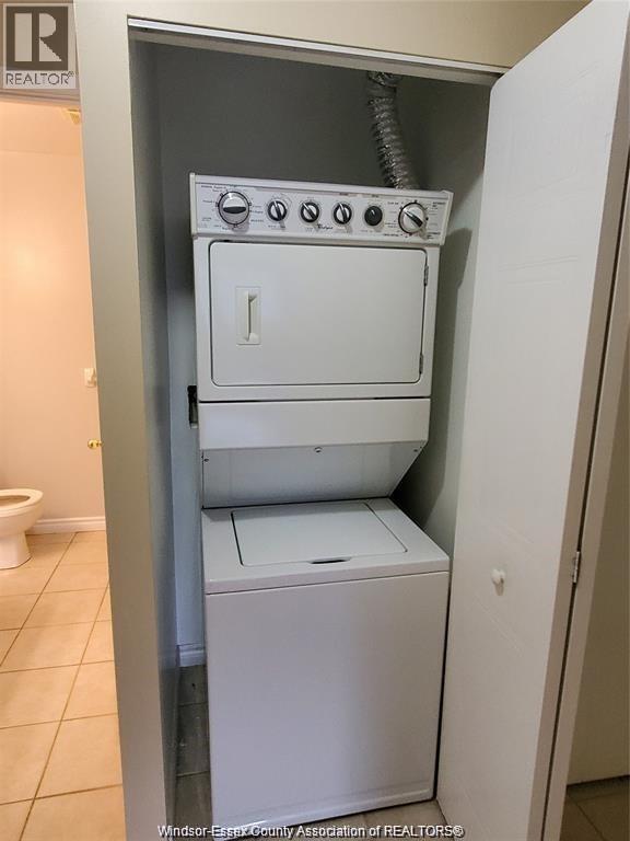 A white dryer and washer are stacked on top of each other in a small space.