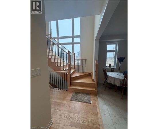 A wooden staircase with a metal railing leads to a dining area with a table set for two.