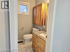 A bathroom with a toilet, sink and wooden cabinets.