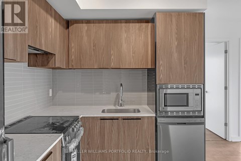 A kitchen with wooden cabinets and a stainless steel dishwasher.