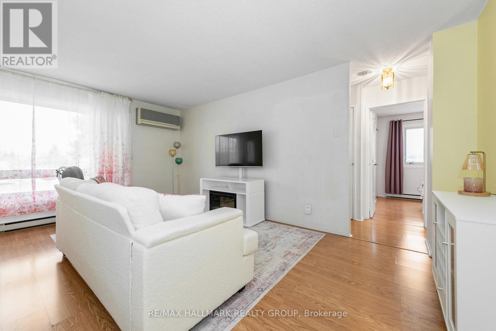 A living room with a white couch and a television on a white stand.