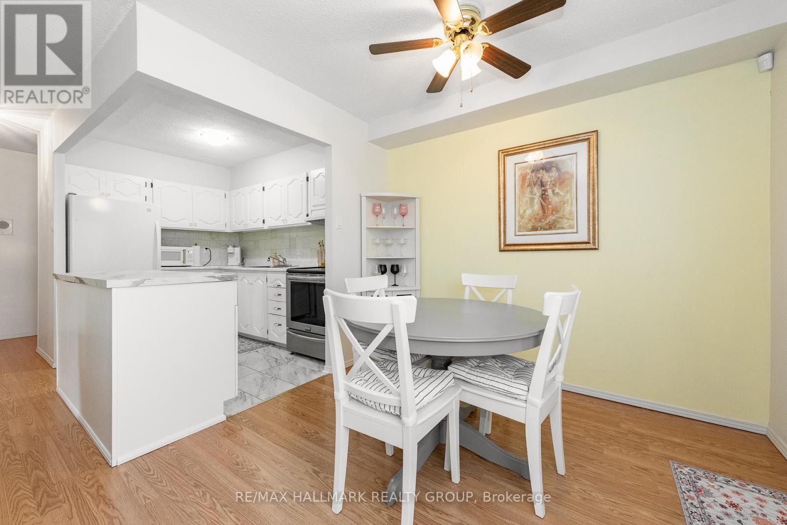 A kitchen with white chairs and a table with a painting on the wall.