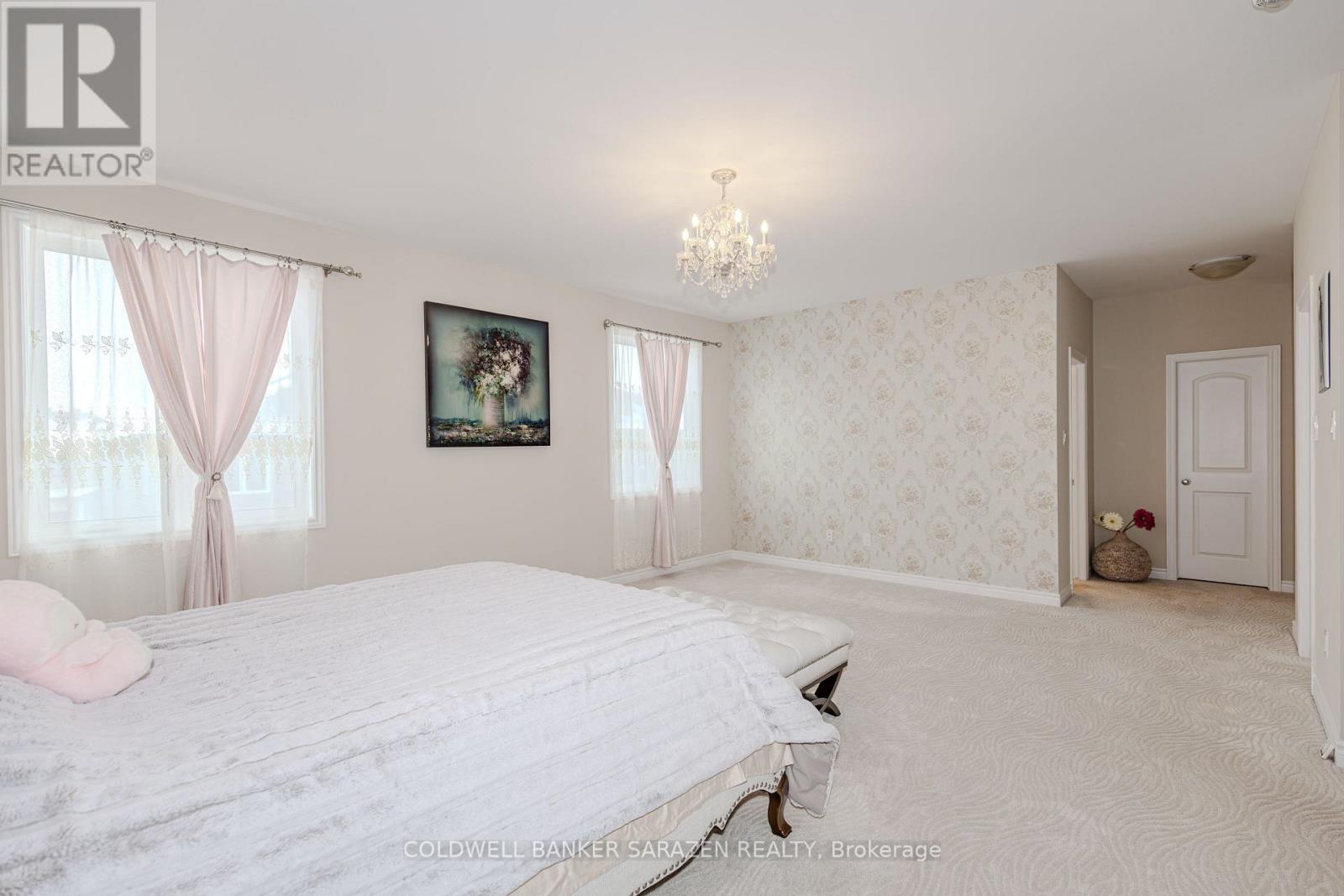 A bedroom with a large bed and a chandelier.