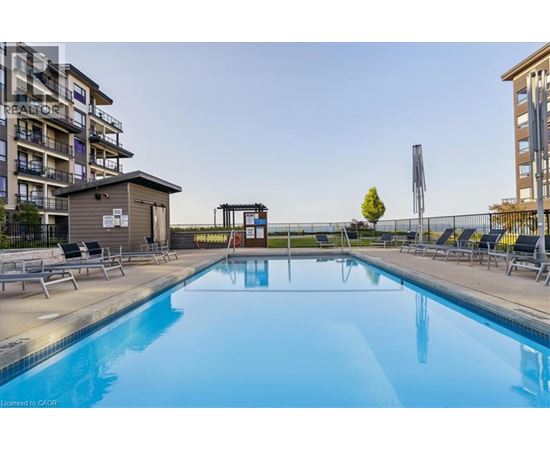 A swimming pool with lounge chairs and a building in the background.