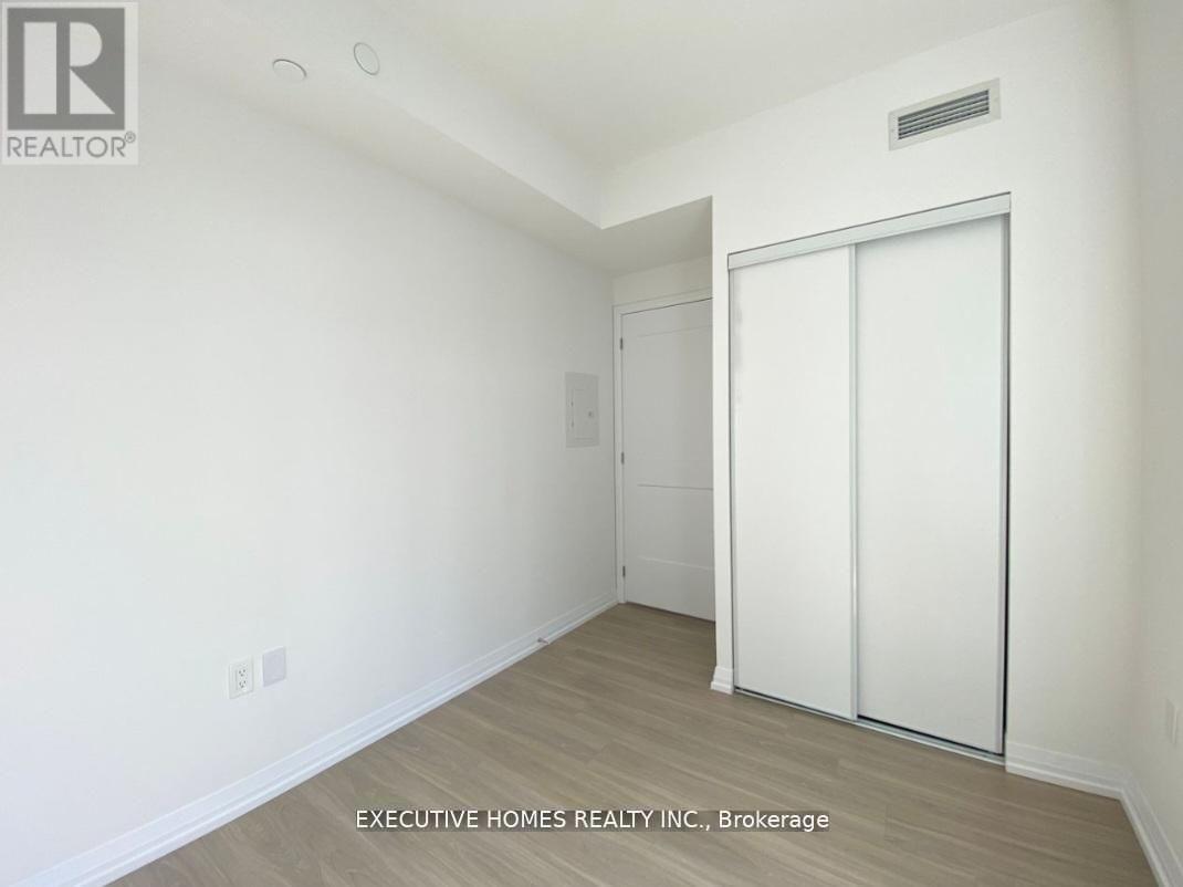 A white bedroom with a sliding door and a brokerage logo.