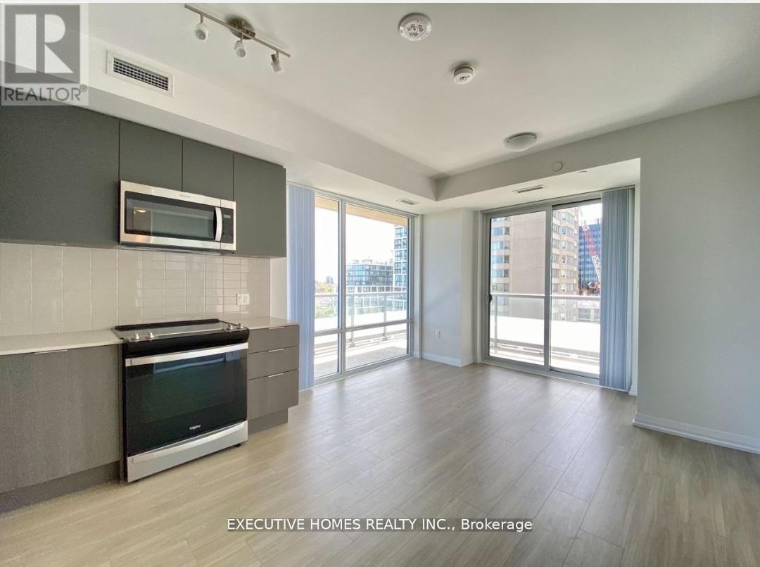 A modern kitchen with a microwave above the stove and a view of the city outside the sliding glass doors.