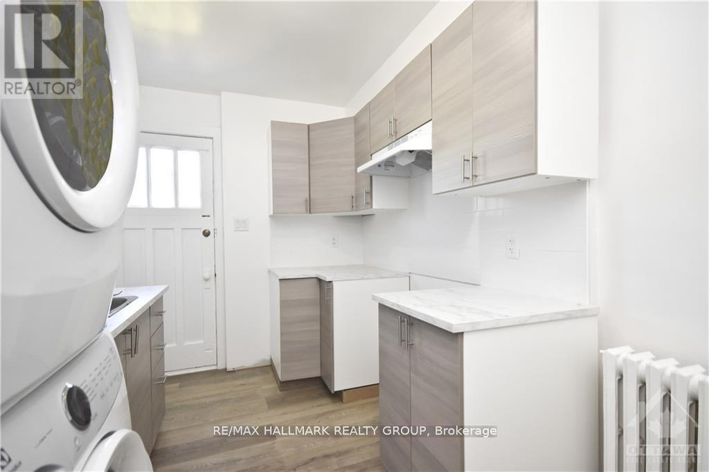 A white kitchen with a washing machine in the foreground.