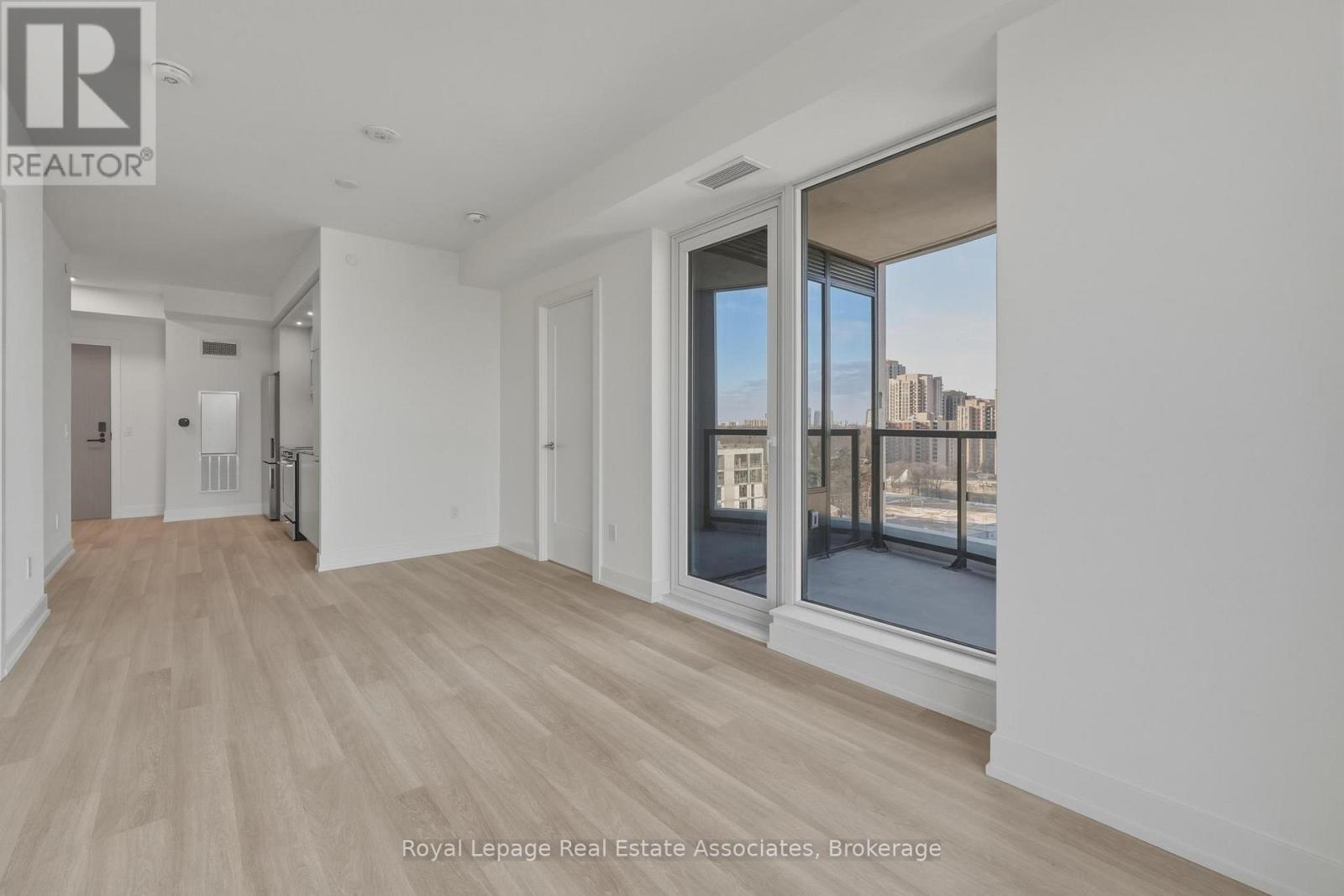 A spacious room with wooden flooring and a large window overlooking a cityscape.