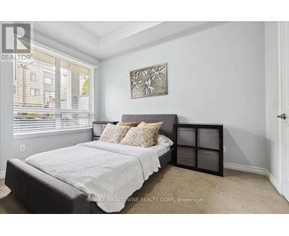 A bedroom with a bed, pillows, and a picture on the wall.