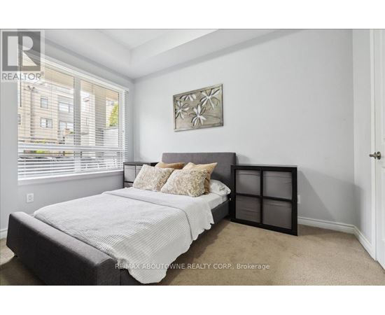 A bedroom with a bed, pillows, and a picture on the wall.