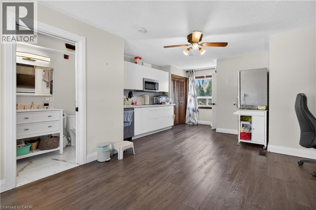 A room with a ceiling fan and a kitchen area with cabinets and a microwave.