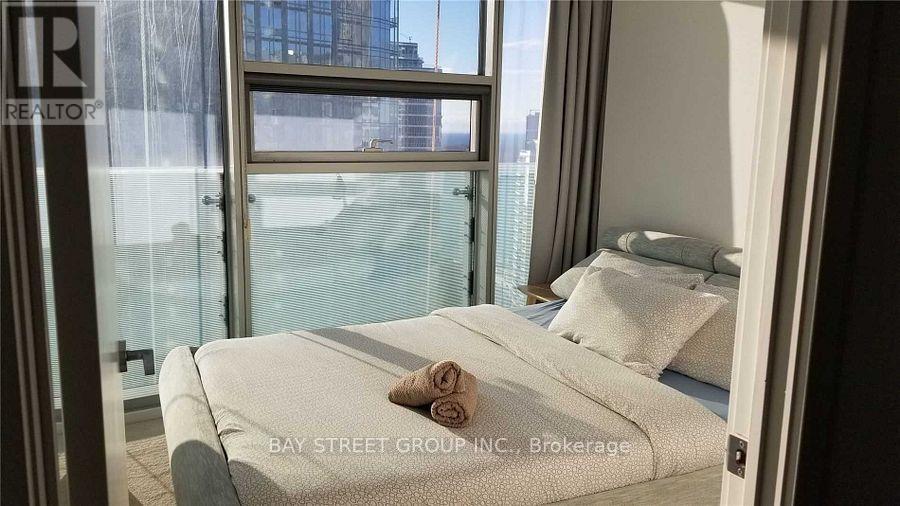 A bedroom with a large bed and a window overlooking a cityscape.