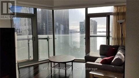A living room with a couch and a table in front of a window overlooking a body of water.