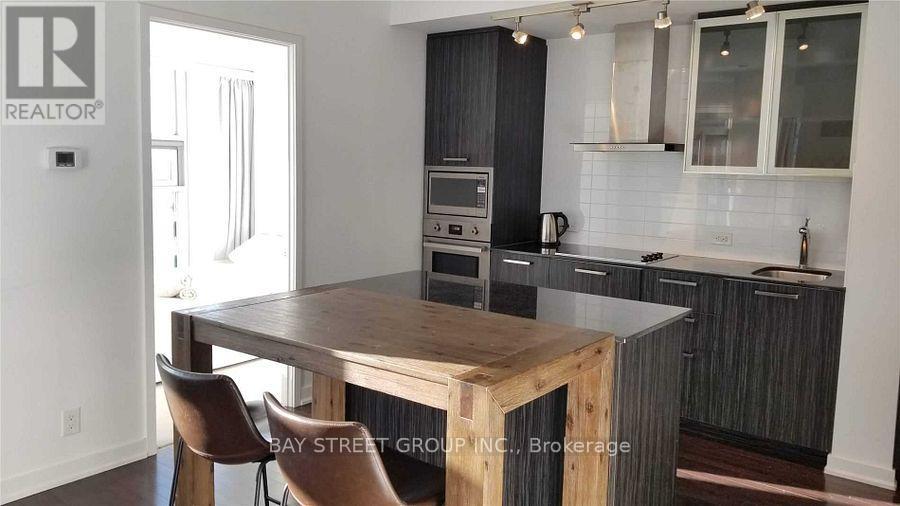 A kitchen with a wooden table and chairs, and a realtor sign on the wall.