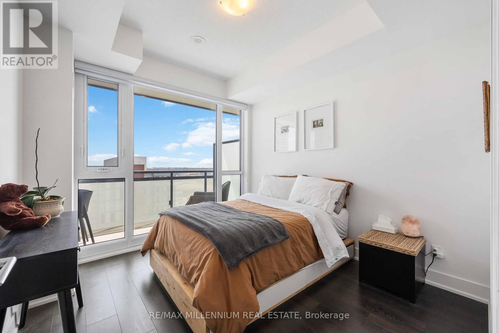 A bedroom with a bed, nightstand, and a window overlooking the city.