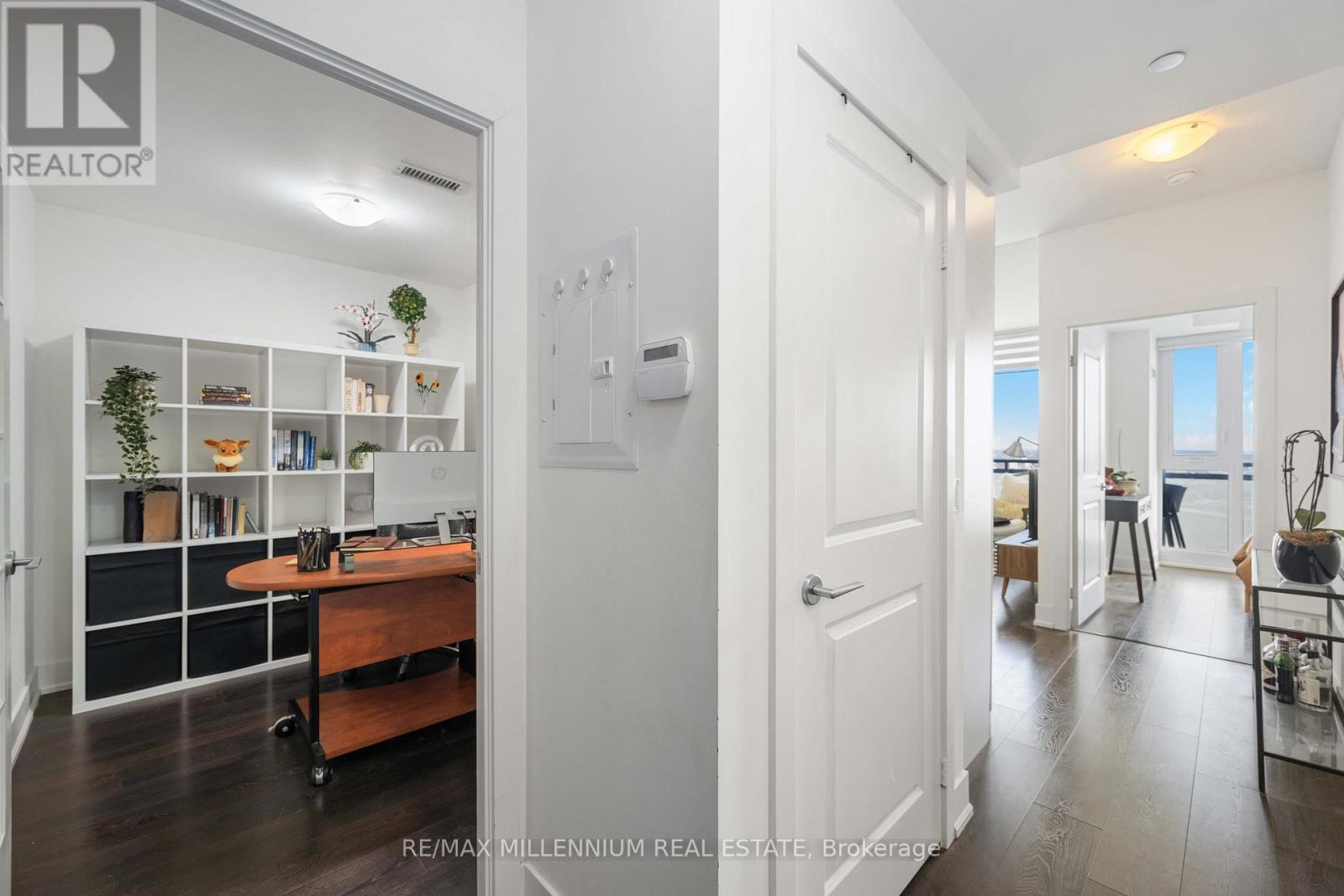 A brokerage sign is on the wall of a well-lit, spacious room with a desk and shelves.