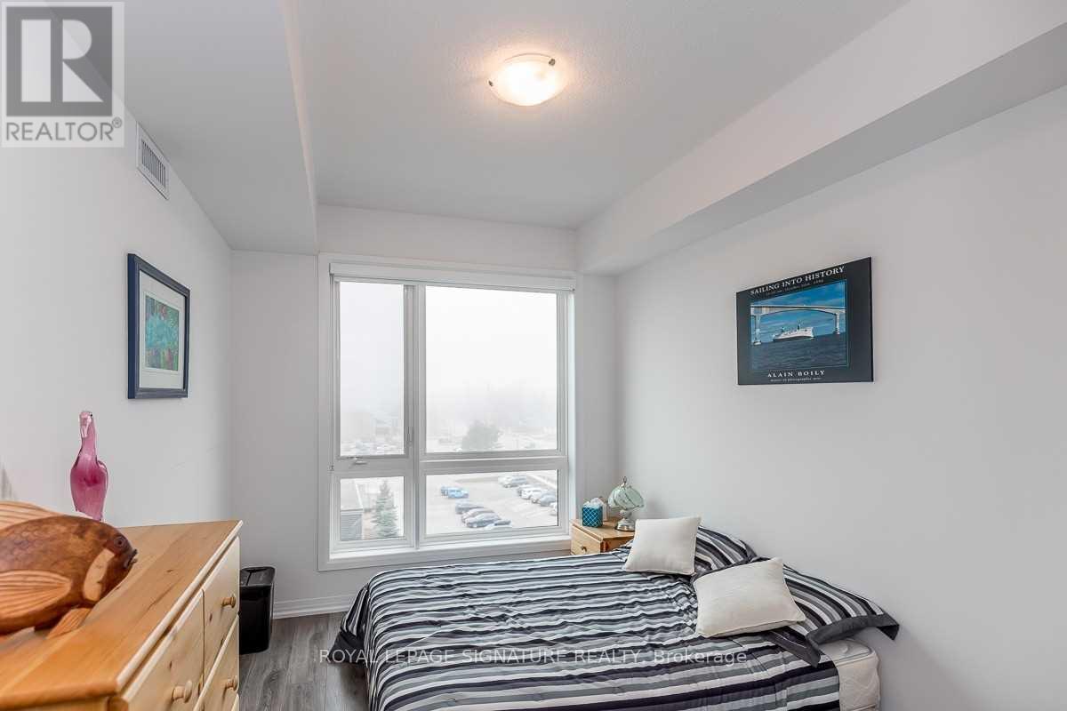 A bedroom with a bed, a dresser, and a window overlooking a parking lot.