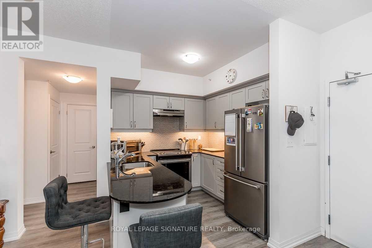 A kitchen with a black chair and a refrigerator.