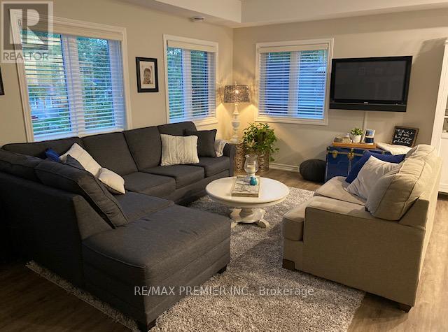 A living room with a grey couch, a white coffee table, and a flat screen TV mounted on the wall.