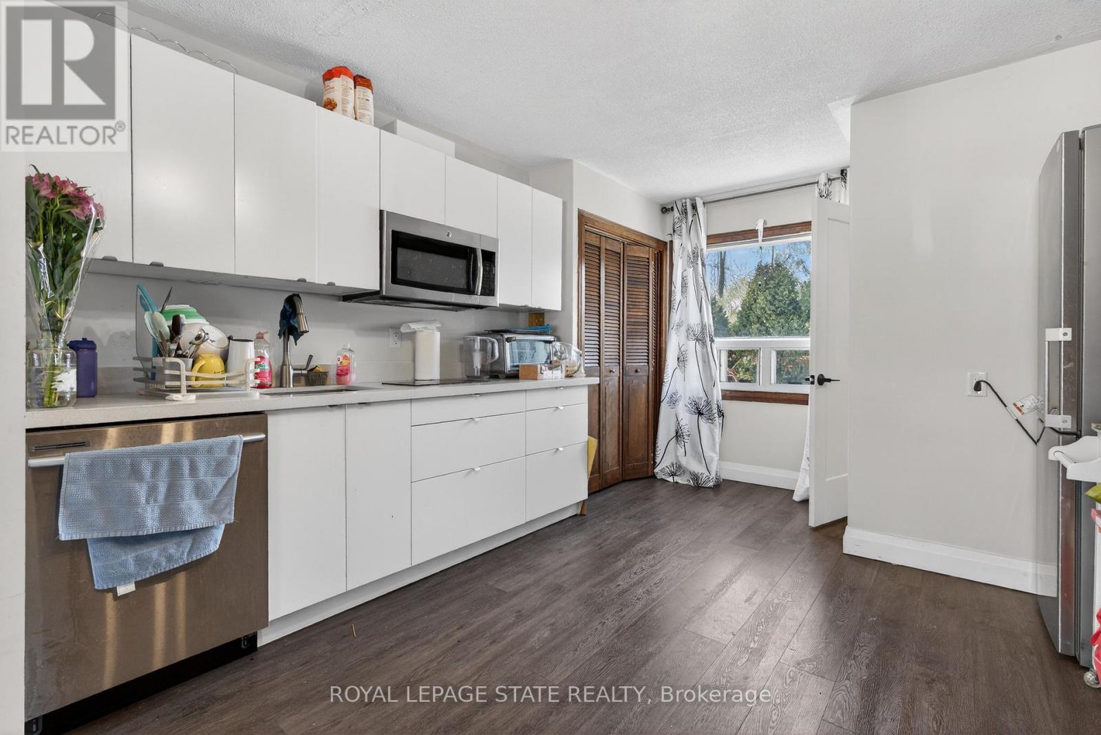 A kitchen with white cabinets and a wooden floor.