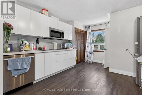 A kitchen with white cabinets and a wooden floor.