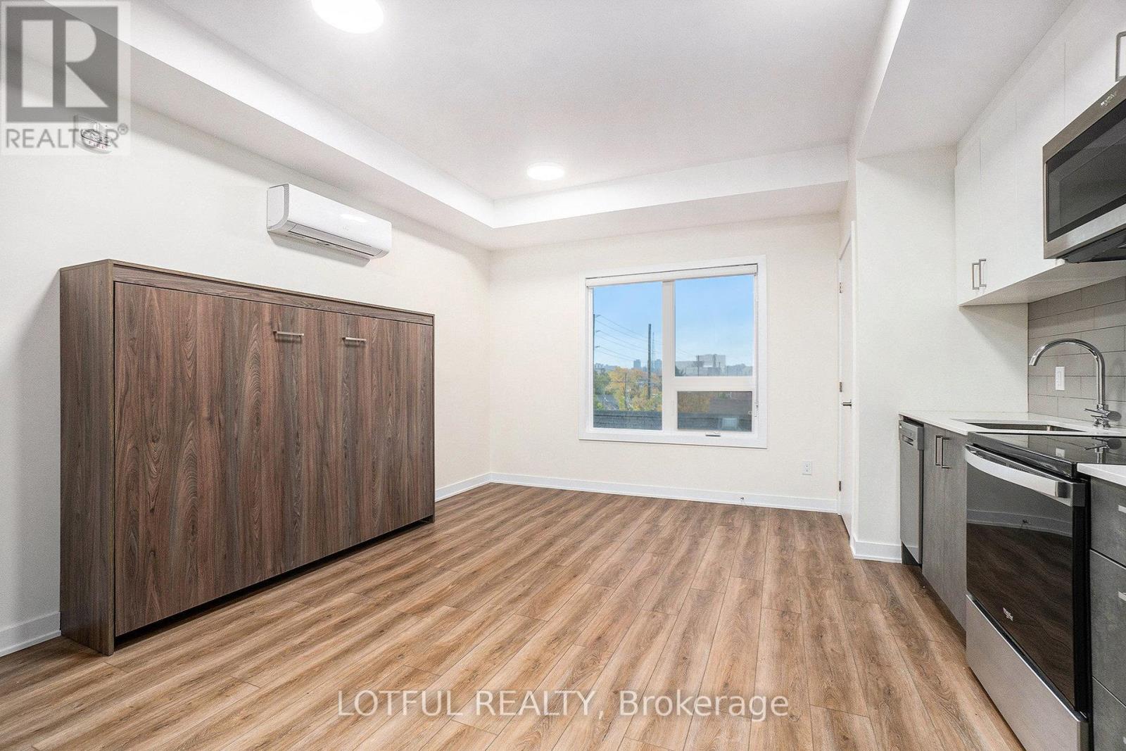 A spacious room with wooden flooring and a large window.