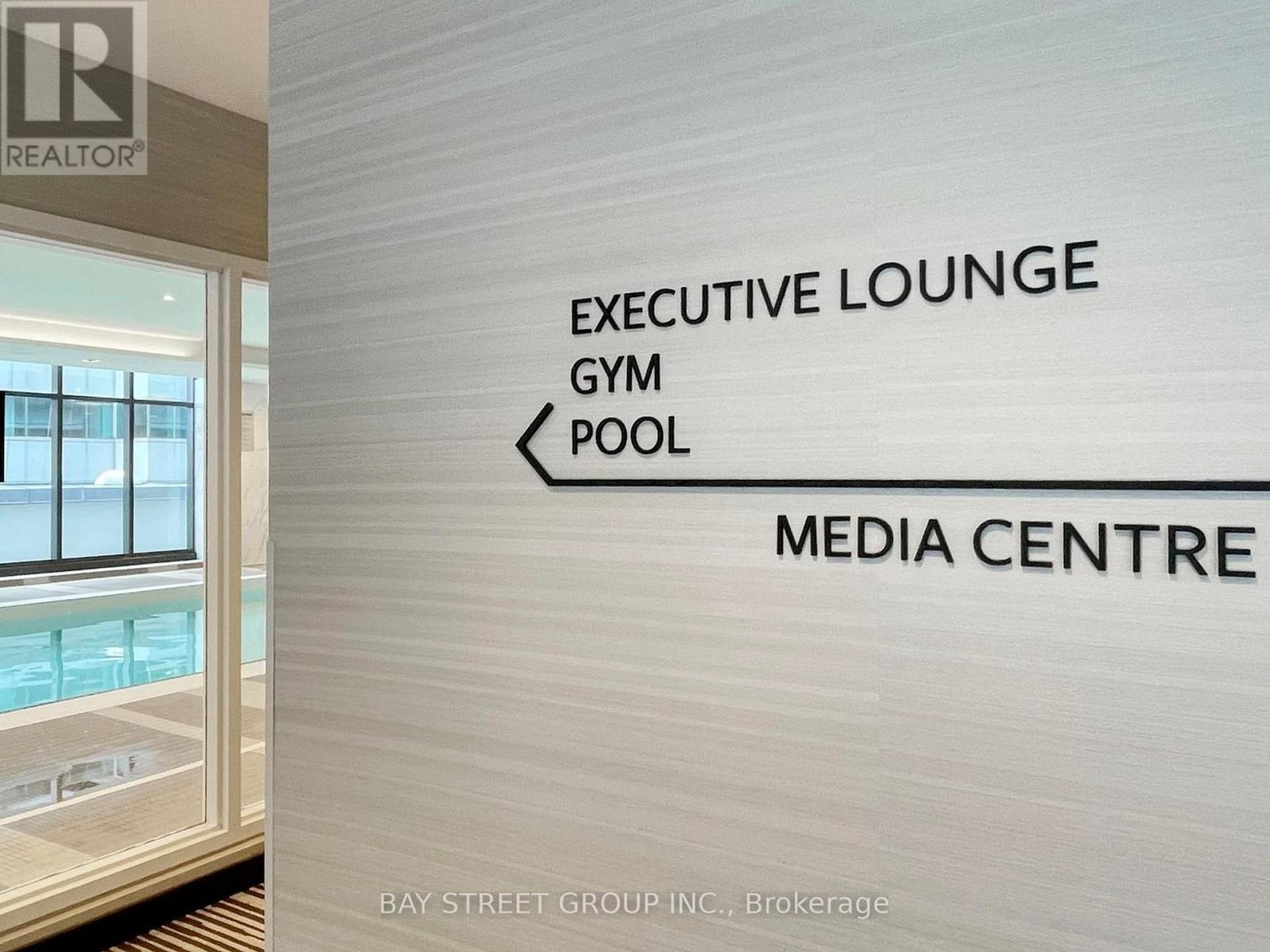 A sign in a room pointing to the Executive Lounge, Gym, Pool, and Media Centre.