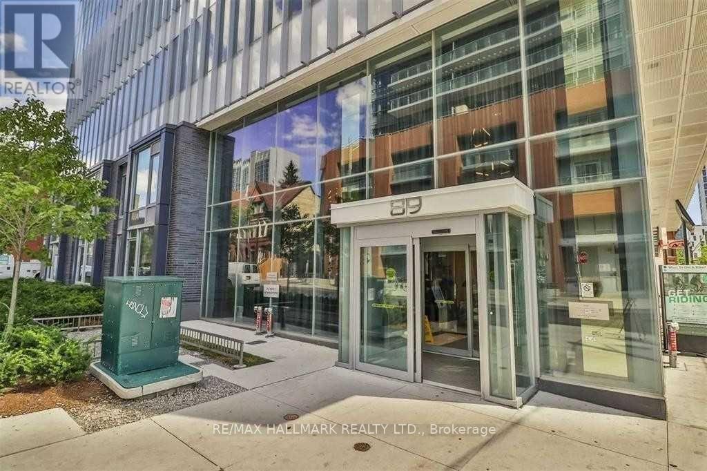 The image shows the front of a building with a glass facade and a sign that reads "RE/MAX HALLMARK REALTY LTD., Brokerage".