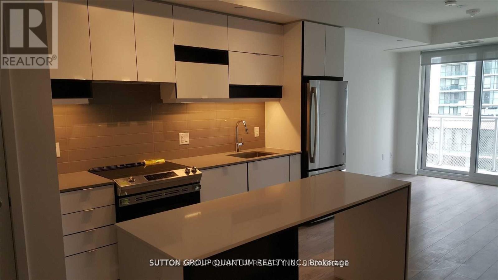 A kitchen with a refrigerator, stove, and cabinets.
