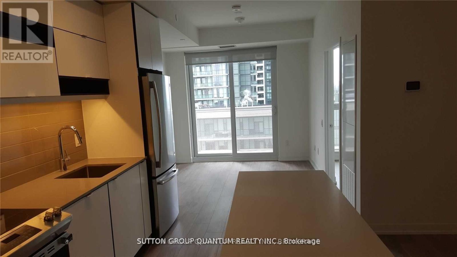 A kitchen with a refrigerator, sink, and stove.