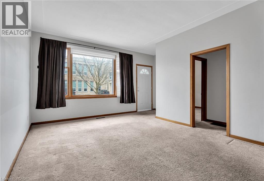 A realtor's image of a carpeted room with a window and a door.