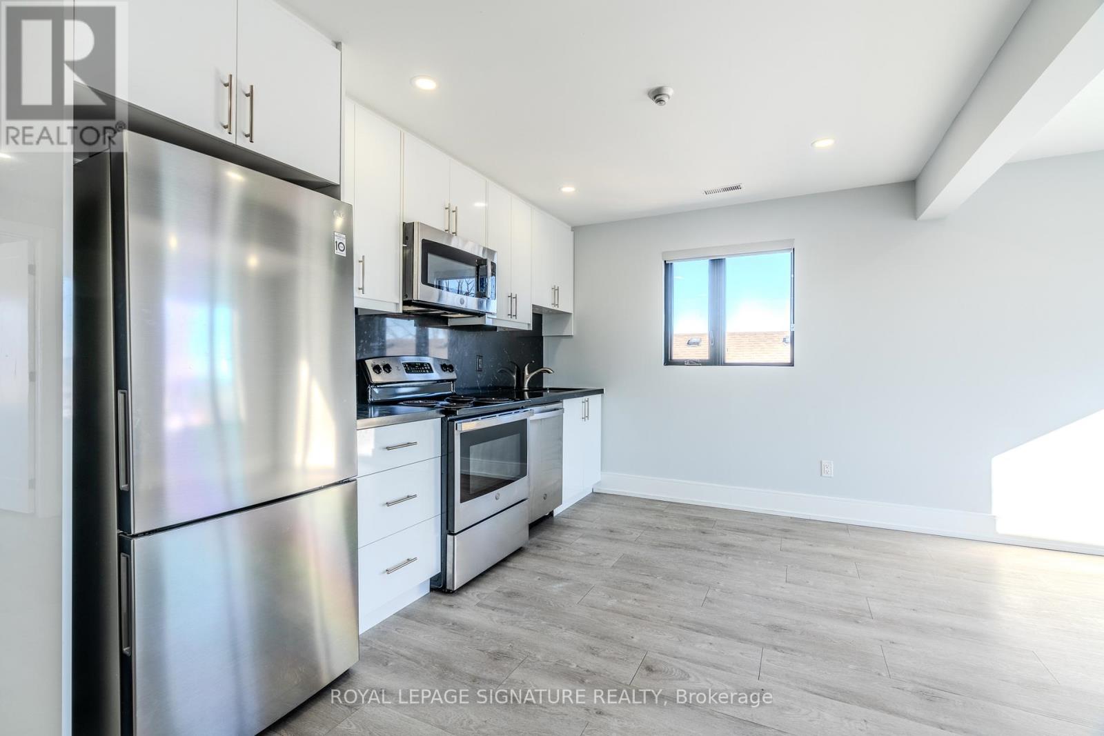 A kitchen with a refrigerator, stove, and microwave.