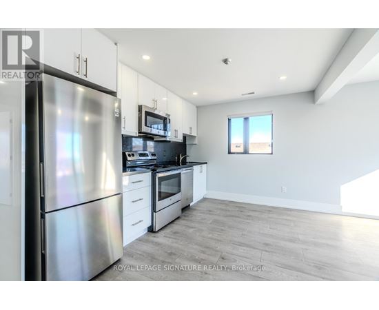 A kitchen with a refrigerator, stove, and microwave.