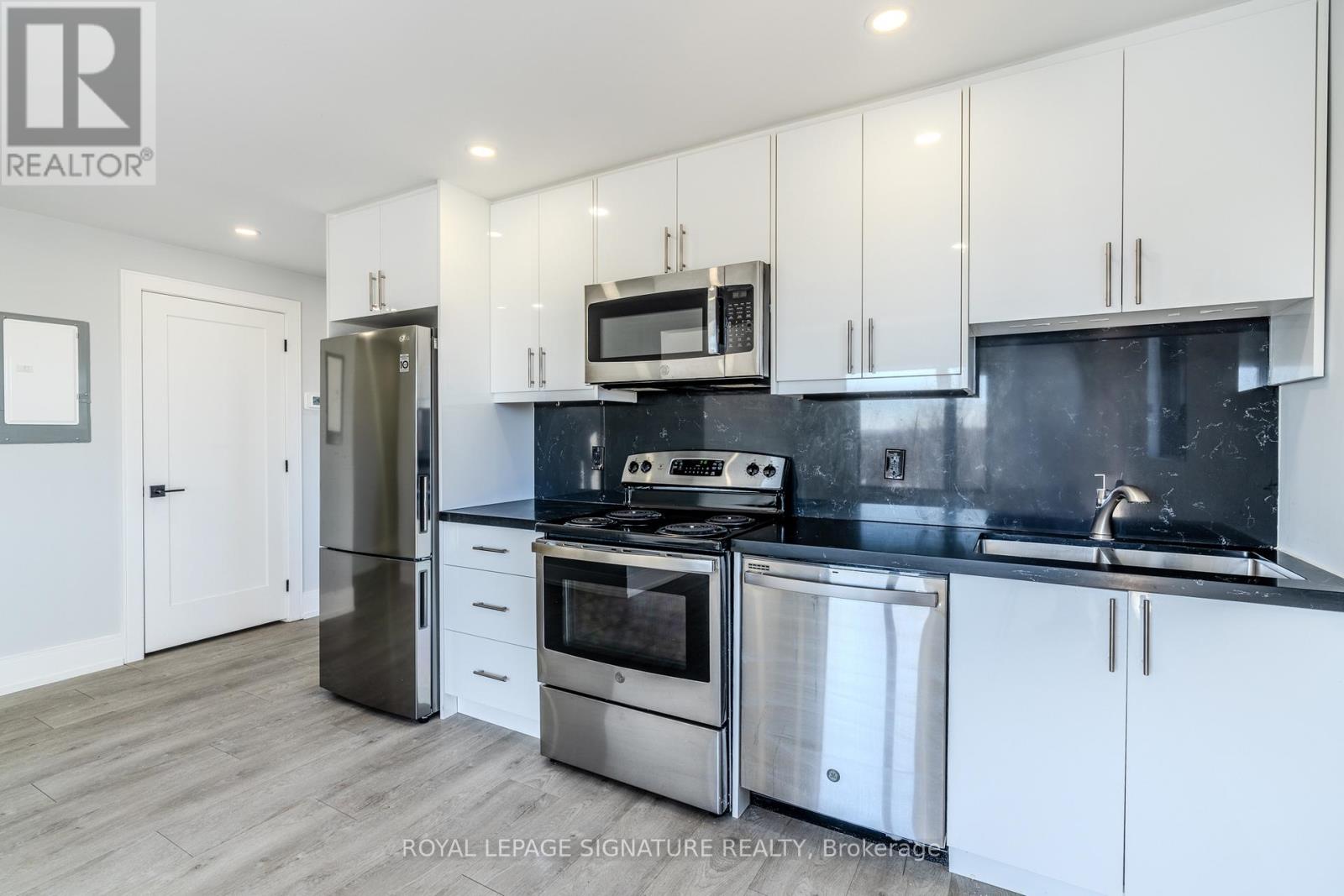 A modern kitchen with white cabinets and stainless steel appliances.