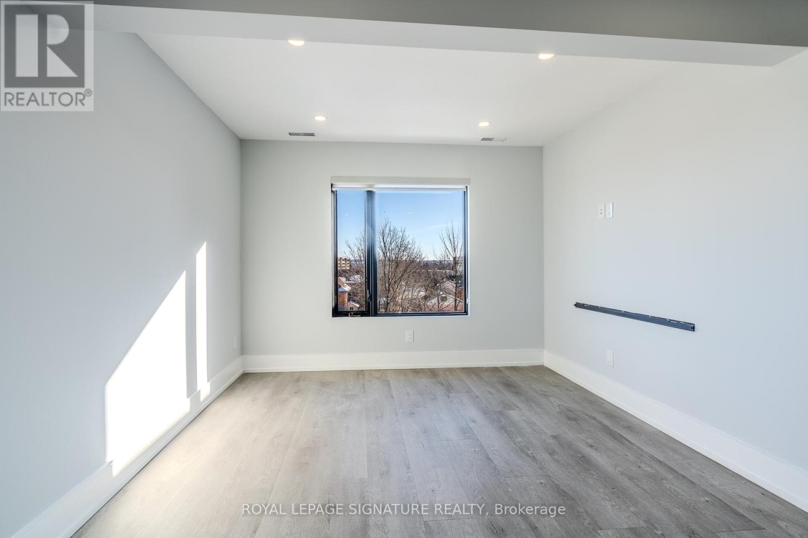 A spacious room with a large window and wooden flooring.