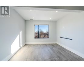 A spacious room with a large window and wooden flooring.