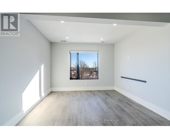 A spacious room with a large window and wooden flooring.