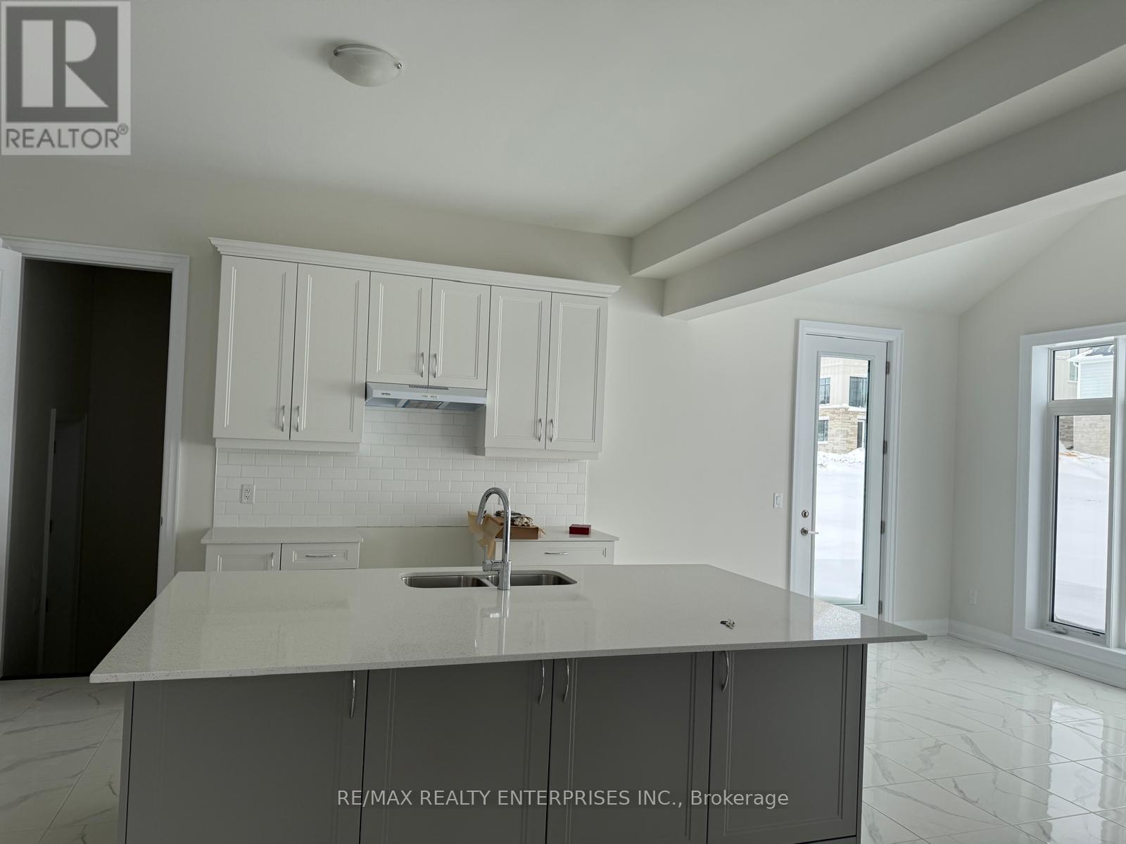 A kitchen with white cabinets and a marble countertop.