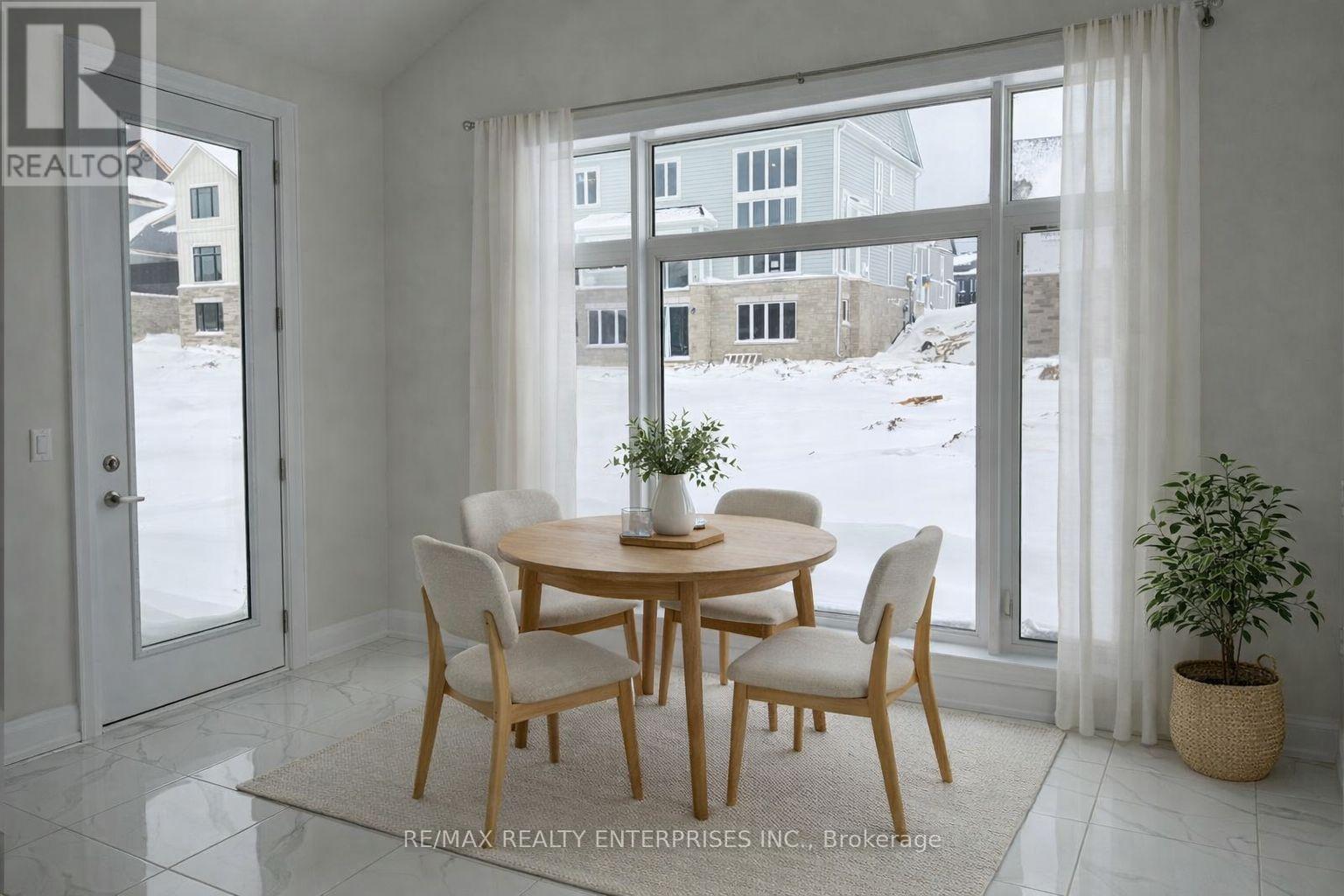 A dining room with a table and chairs in front of a large window.