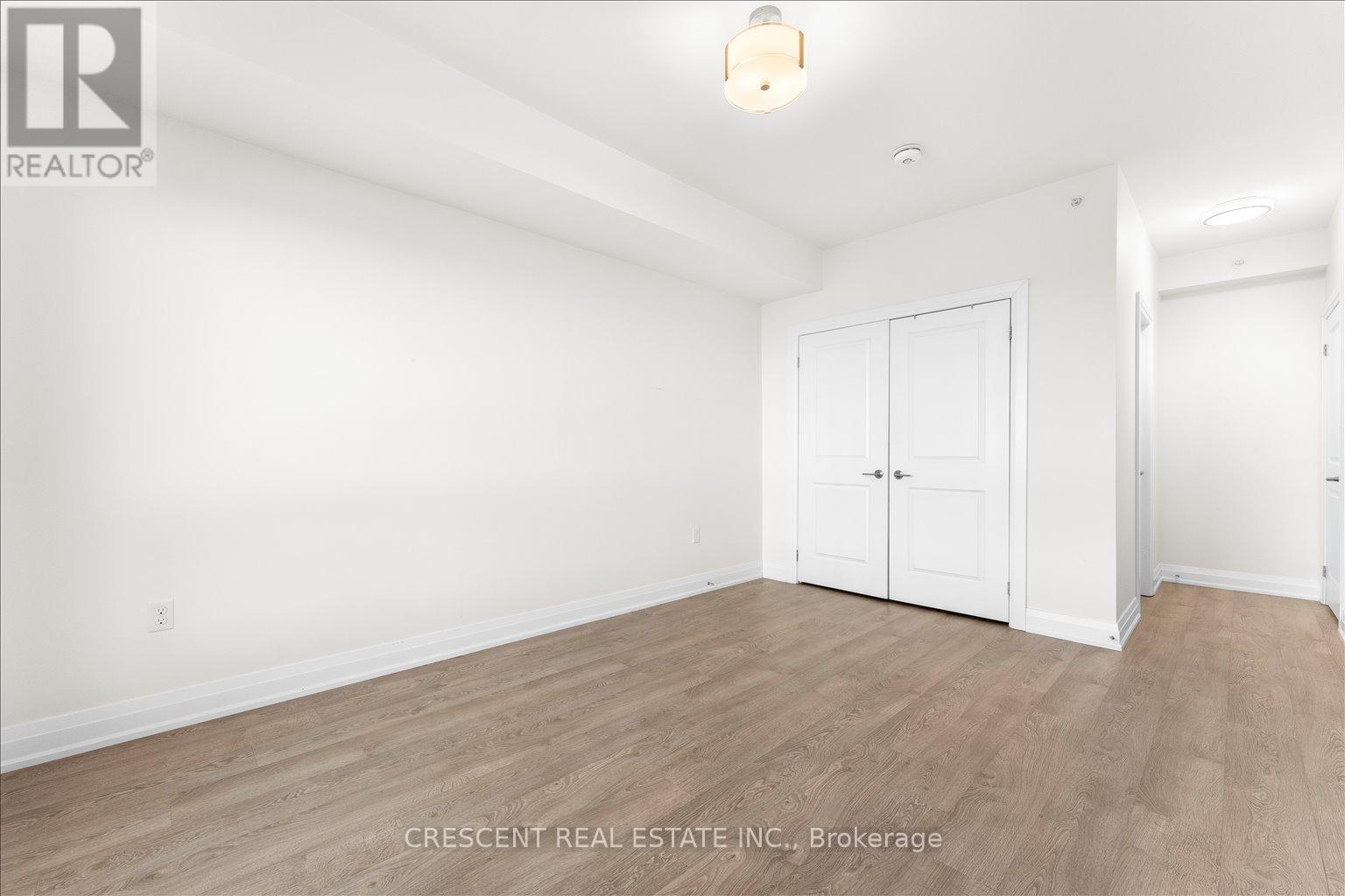 A white bedroom with wood flooring and a single door.