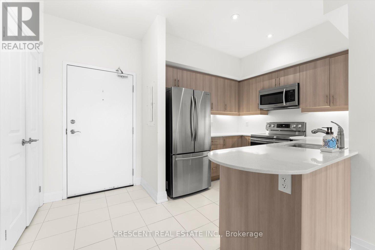 A kitchen with a refrigerator, microwave, and oven.