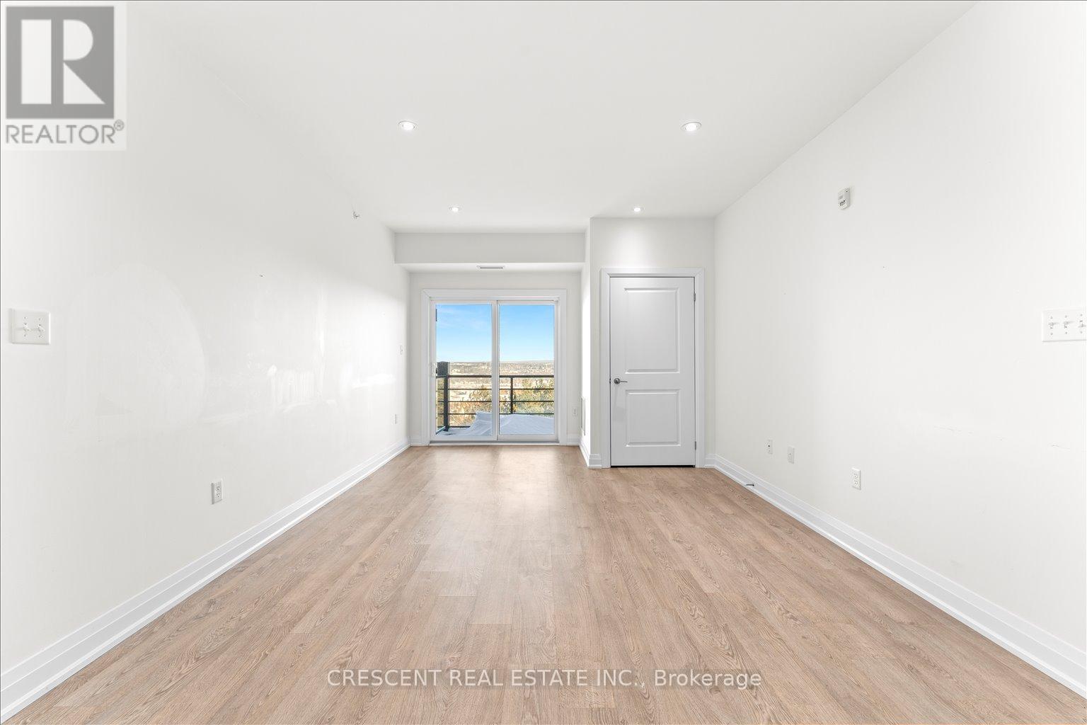 A spacious room with wood flooring and a doorway leading to a balcony.